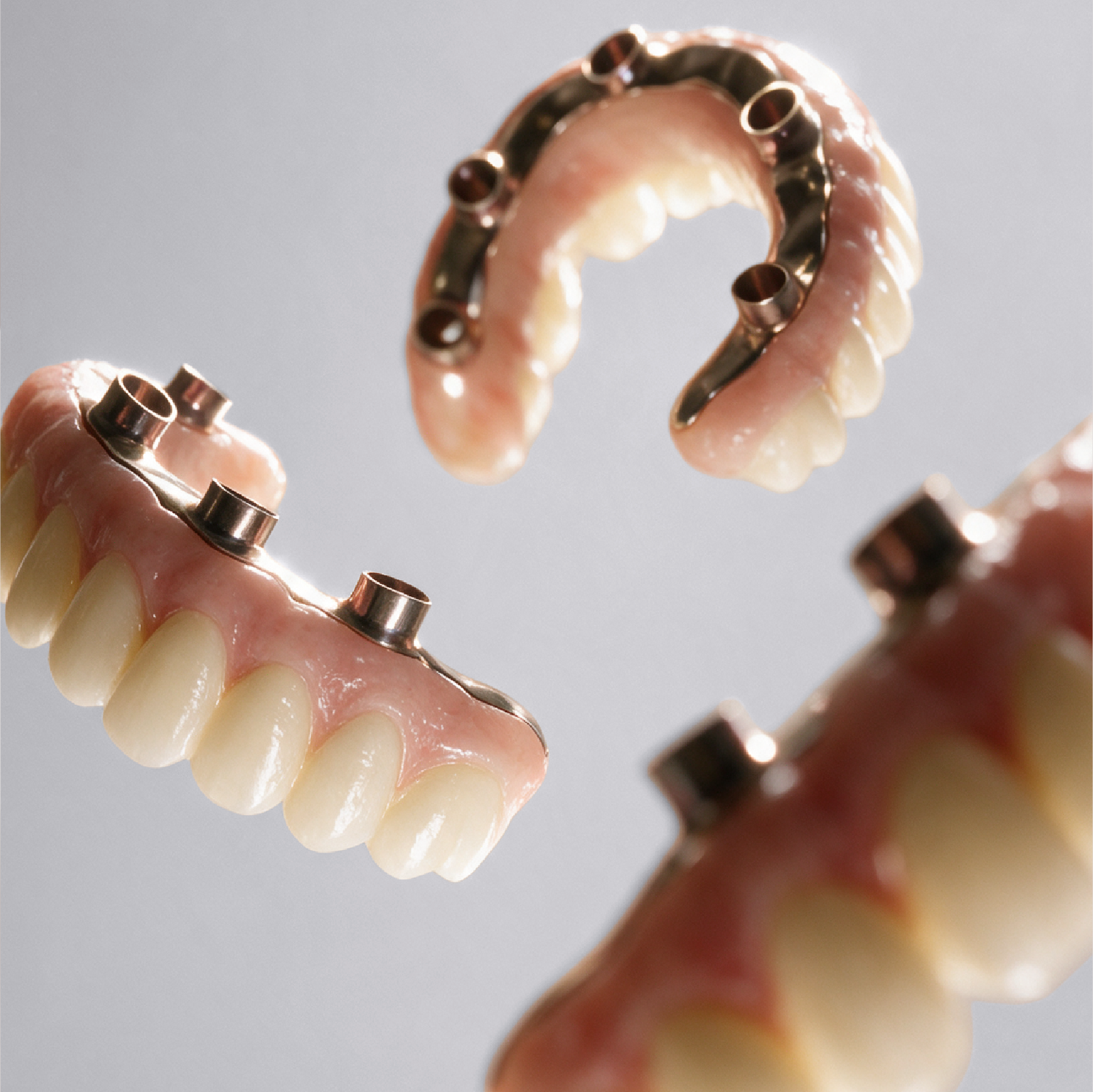 Prótesis dentales sobre implantes flotando sobre fondo gris claro